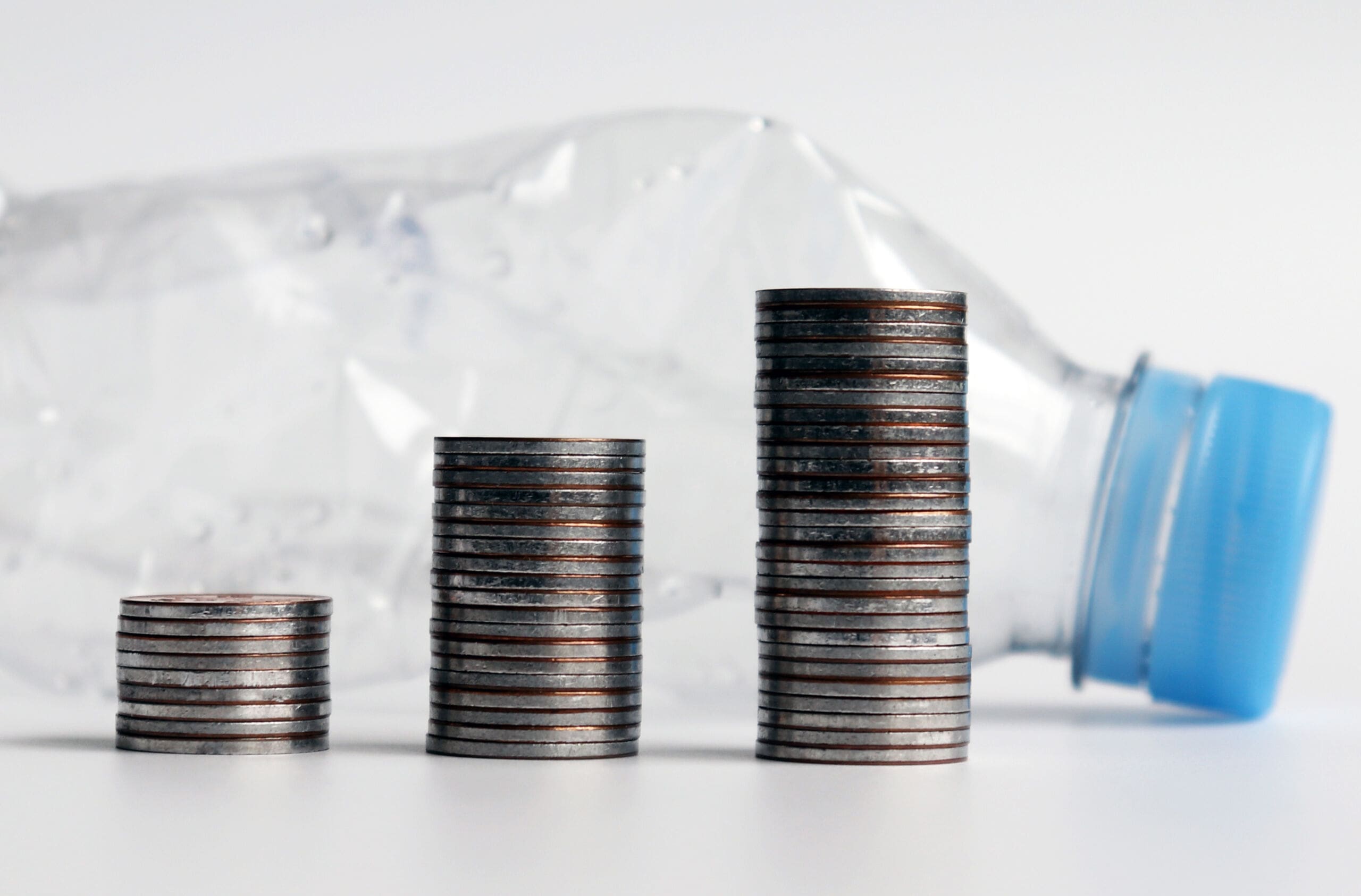 Three piles of coins and disposable plastic products.